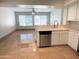 Kitchen with stainless steel dishwasher, eat-in counter, white cabinetry, and view into living space at 4034 E Anderson Dr, Phoenix, AZ 85032
