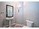Stylish powder room with a pedestal sink, elegant mirror, and modern lighting, offering a touch of sophistication at 40613 N Candlewyck Ln, Anthem, AZ 85086