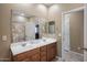 Bright bathroom featuring double sinks, large mirror, tile flooring, and shower with tile surround at 4230 W Palace Station Rd, New River, AZ 85087