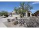 Single-story home with two car garage, xeriscaping and tree at 5418 W Carson Rd, Laveen, AZ 85339