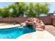 Backyard pool with rock waterfall feature, travertine decking and privacy wall at 6317 S Banning St, Gilbert, AZ 85298