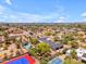 Scenic aerial shot of a neighborhood featuring homes with swimming pools, green spaces, and community tennis courts at 8213 E Sharon Dr, Scottsdale, AZ 85260