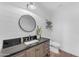 Half bathroom with a black vanity and a round mirror above the sink at 8213 E Sharon Dr, Scottsdale, AZ 85260