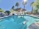Beautiful pool area with covered lounge space, palm trees, and clear blue skies at 8213 E Sharon Dr, Scottsdale, AZ 85260