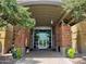 Grand entrance to the community center with brick columns, lush greenery, and a modern glass facade at 8422 W Mantle Way, Florence, AZ 85132