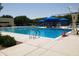 Large community pool with lap lanes, blue umbrellas, and lounge chairs, perfect for relaxing and swimming at 8422 W Mantle Way, Florence, AZ 85132