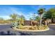 Desert Village entrance featuring native plants, including cacti, succulents, and a palm tree, with a stone monument sign at 8848 E Conquistadores Dr, Scottsdale, AZ 85255