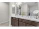 Bathroom with double sinks, dark wood cabinetry, and large mirrors with modern fixtures at 19606 W Grant St, Buckeye, AZ 85326