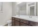 Bright bathroom features a double vanity with dark wood cabinets, white countertops and a large mirror at 19606 W Grant St, Buckeye, AZ 85326