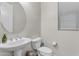 Bright powder room featuring pedestal sink, rounded mirror, and toilet with white fixtures and a window at 19606 W Grant St, Buckeye, AZ 85326