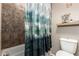 Well-lit bathroom featuring a shower with decorative curtain, toilet, and tiled walls at 27189 N 75Th Dr, Peoria, AZ 85383