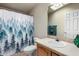 Well-lit bathroom with a stylish forest shower curtain and tile countertop at 3301 S Goldfield Rd # 1048, Apache Junction, AZ 85119