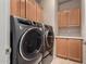 Laundry room with modern gray front-load washer and dryer and wood cabinets at 3301 S Goldfield Rd # 1048, Apache Junction, AZ 85119