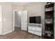 Bedroom with plank flooring featuring a TV, storage console, and an open doorway at 3719 E Sandy Way, Gilbert, AZ 85297