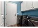 A bright laundry room with a dark front-loading washer and dryer, and white cabinets at 3719 E Sandy Way, Gilbert, AZ 85297