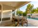Covered patio dining area with a wooden table and chairs, complemented by a view of the pool and landscaping at 3884 S Wilson Dr, Chandler, AZ 85286