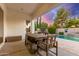 Covered patio with wood table, chairs, and seating with a sunset view over the pool at 3884 S Wilson Dr, Chandler, AZ 85286