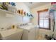 Functional laundry room with washer, dryer, sink, storage shelves, and a window at 45138 W Norris Rd, Maricopa, AZ 85139
