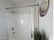 Clean bathroom with a white tub and shower featuring neutral tile and a plant for decor at 4608 W Gail Dr, Chandler, AZ 85226