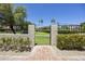 Brick path leads to gated entrance with beautiful landscaping and view of common areas beyond at 10538 E Gold Dust Cir, Scottsdale, AZ 85258