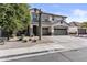 Inviting two-story home displaying a three-car garage, desert landscaping, and a vibrant green tree under a clear blue sky at 11521 E Quintana Ave, Mesa, AZ 85212