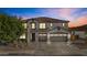 Striking two-story home showcasing a three-car garage, desert landscaping, and a tile roof against a colorful twilight sky at 11521 E Quintana Ave, Mesa, AZ 85212