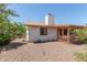Exterior of home and backyard with gravel landscaping, chimney, covered patio, and some foliage in view at 136 E San Angelo Ave, Gilbert, AZ 85234
