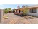 View of the home's exterior from the backyard featuring a covered patio, gravel landscaping, and mature trees at 136 E San Angelo Ave, Gilbert, AZ 85234
