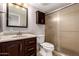 Bathroom with light tile walls, shower, toilet, and dark wooden cabinets and drawers below the sink at 19601 N 7Th St # 1022, Phoenix, AZ 85024