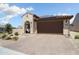 Single-Gathering home showcases a stucco facade, a brown garage door, and desert landscaping with a brick paver driveway at 26824 W Ponderosa Ln, Buckeye, AZ 85396