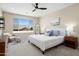 A bright main bedroom with a ceiling fan, large windows, and neutral decor with decorative pillows and artwork at 26824 W Ponderosa Ln, Buckeye, AZ 85396