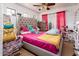 A room features a large bed with pink sheets, a yellow chair, and bright decor at 2721 N 107Th Dr, Avondale, AZ 85392