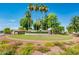 Attractive community entrance featuring lush landscaping, mature palm trees, and colorful flowerbeds at 2721 N 107Th Dr, Avondale, AZ 85392