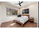 Comfortable bedroom with light walls, ceiling fan, modern art and a window showcasing the outdoor scenery at 28768 N 95Th Way, Scottsdale, AZ 85262