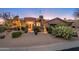 Charming home at dusk featuring desert landscaping, beautiful lighting, and a three car garage at 28768 N 95Th Way, Scottsdale, AZ 85262