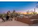 Outdoor kitchen area featuring a built-in grill, seating, and desert landscaping against a colorful twilight sky at 28768 N 95Th Way, Scottsdale, AZ 85262