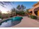 Backyard oasis with a freeform pool, mature landscaping, and comfortable outdoor seating area at twilight at 28768 N 95Th Way, Scottsdale, AZ 85262