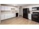 Modern kitchen featuring white cabinets, light countertops, black appliances, and vinyl plank flooring at 3118 W Aster Dr, Phoenix, AZ 85029