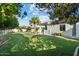 Backyard featuring a lush lawn, mature trees, outdoor kitchen, and covered patio at 3354 E Jaeger Cir, Mesa, AZ 85213