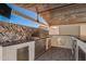 This outdoor kitchen has a stainless steel grill, brick backsplash and a wooden slat roof at 4654 W Suncup Dr, San Tan Valley, AZ 85144