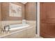Relaxing bathroom showcases a soaking tub with stone tile surround and decorative wall art at 4909 N Woodmere Fairway -- # 1004, Scottsdale, AZ 85251