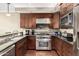 Close-up of a modern kitchen with stainless steel appliances, granite countertops, and dark wood cabinetry for ample storage at 4909 N Woodmere Fairway -- # 1004, Scottsdale, AZ 85251