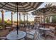 Inviting outdoor patio with striped umbrellas, tables and chairs, with lush palm trees in the background at 4909 N Woodmere Fairway -- # 1004, Scottsdale, AZ 85251
