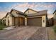 Charming single-story home with stone accents, a tile roof, manicured lawn and a brick paver driveway at 6954 W Maya Way, Peoria, AZ 85383