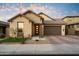 Charming single-story home with stone accents, a tile roof, manicured lawn and a brick paver driveway at 6954 W Maya Way, Peoria, AZ 85383