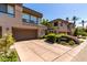 Townhome showcases a two-car garage with lush landscaping, a well-maintained driveway, and a sunny day at 7400 E Gainey Club Dr # 203, Scottsdale, AZ 85258