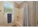 This bathroom features a shower and tub combination with a decorative curtain and a window at 7658 W Boca Raton Rd, Peoria, AZ 85381