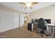 Carpeted bedroom with a ceiling fan, closet, and a dedicated desk space at 7658 W Boca Raton Rd, Peoria, AZ 85381