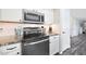A kitchen with stainless steel stove, microwave, white cabinets, tiled backsplash and granite countertops at 7658 W Boca Raton Rd, Peoria, AZ 85381
