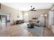 Open-concept living room with wood-look tile, neutral decor, ceiling fan, and ample natural light from large windows at 7658 W Boca Raton Rd, Peoria, AZ 85381
